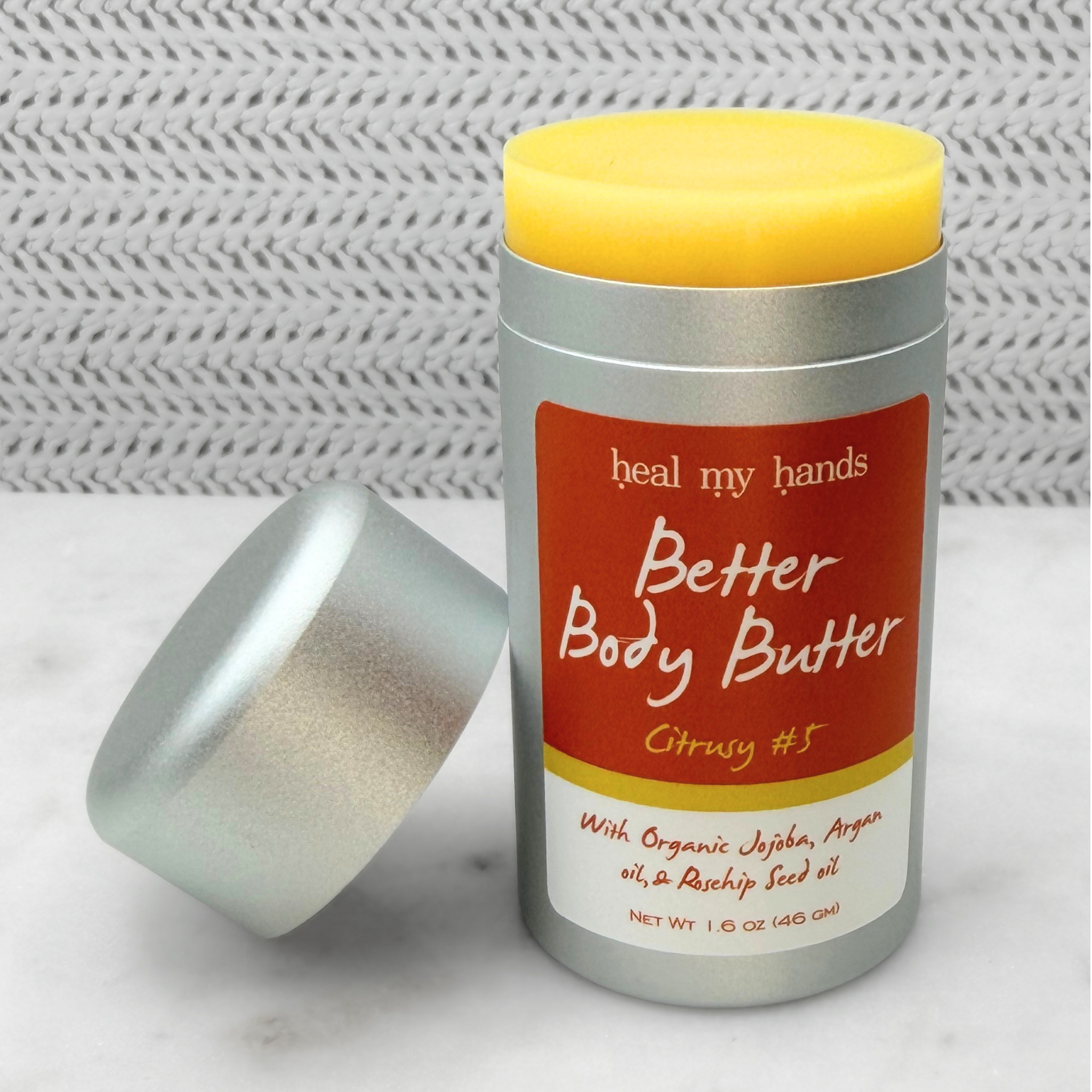 Open push up tube of Better Body Butter in Citrusy #5 on a textured surface.