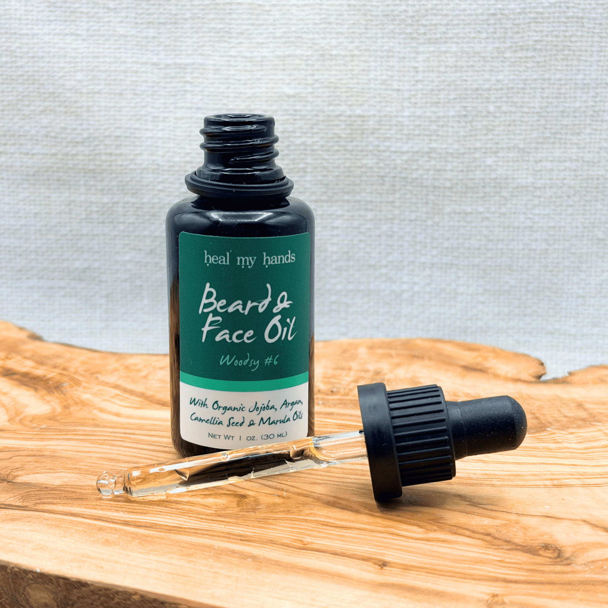 Beard and face oil bottle with dropper on a wooden surface