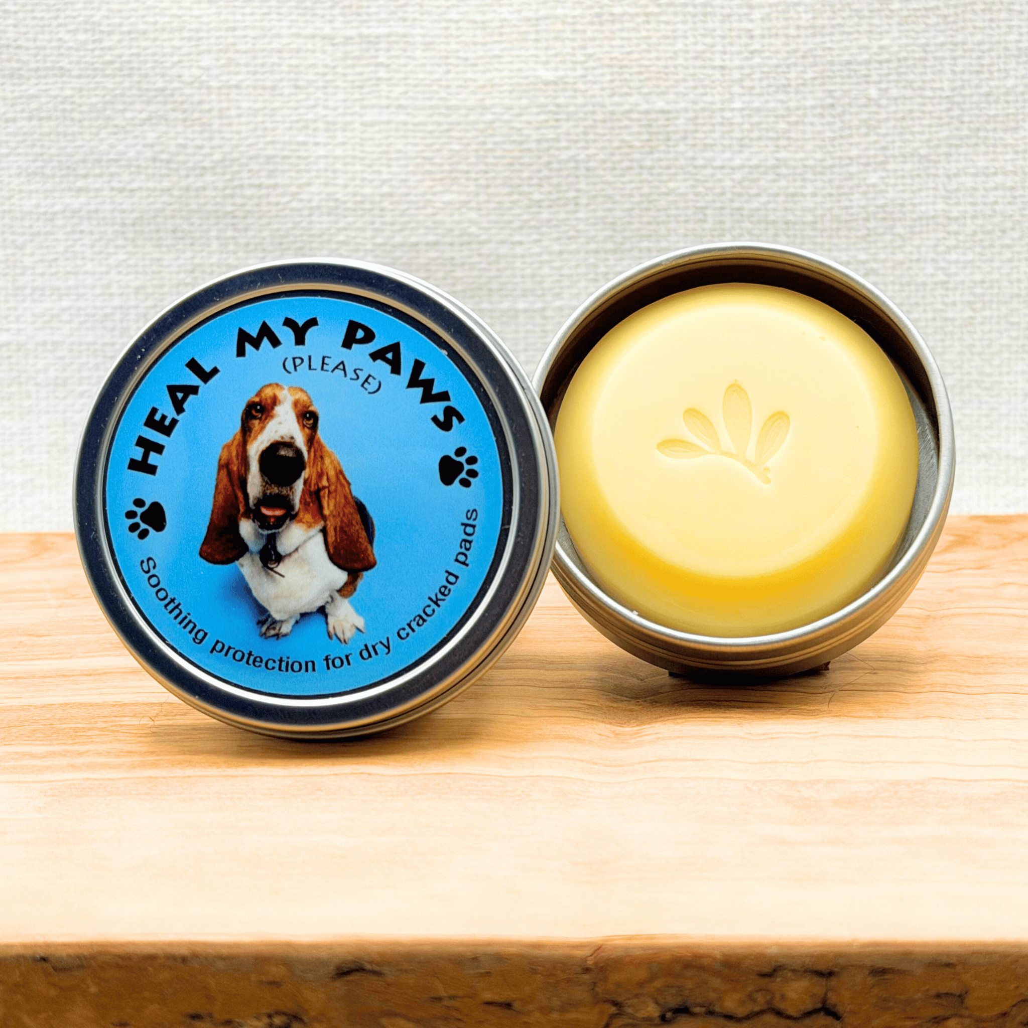 Heal My Paws Moisturizing bar in a tin on a wooden surface.