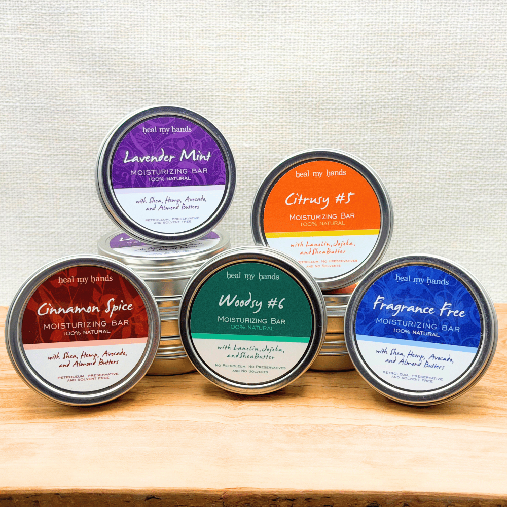 Assorted Regular Strength Moisturizing Bars in assorted scents on wood surface with textured cream background.