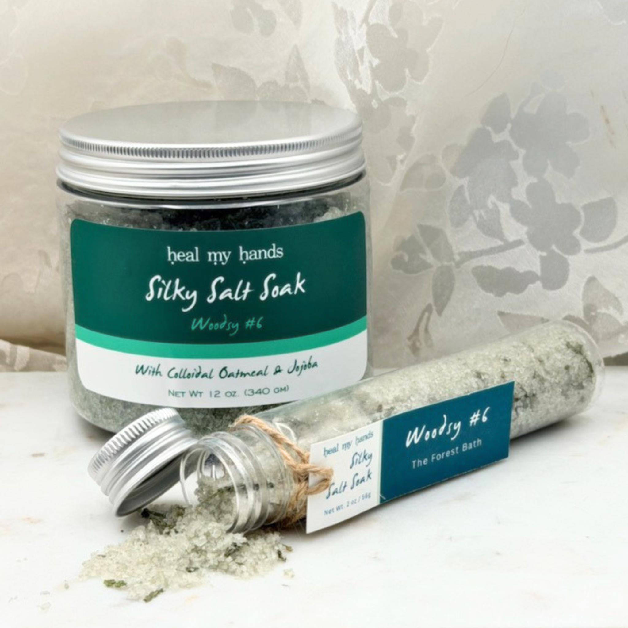 Woodsy #6 Silky Salt Soak 12 oz jar and 2 oz vial on marble surface.