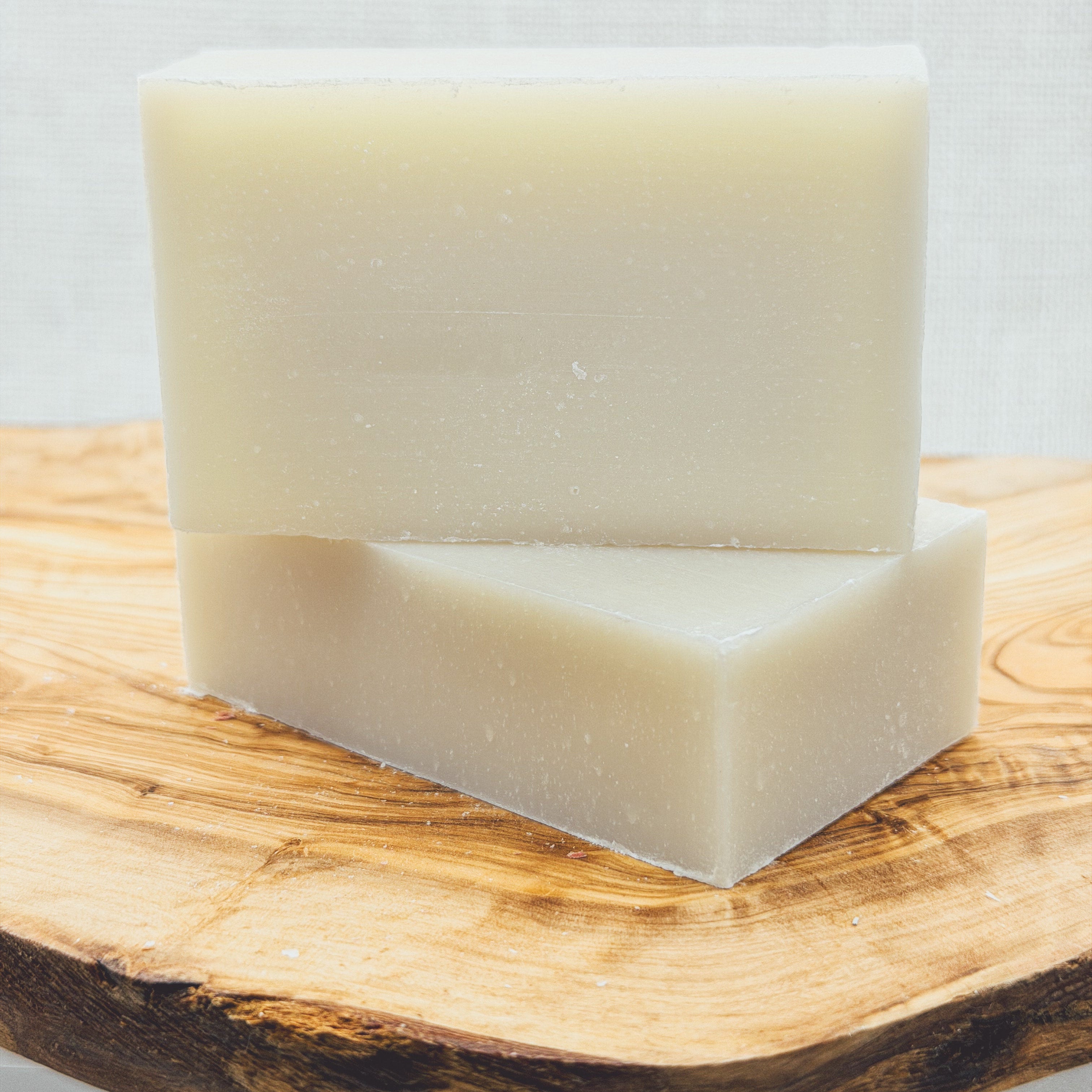 Two bars of soap on a wooden surface with a light gray background