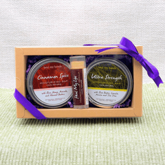 Set of moisturizing bars and lip balm in a box with a purple ribbon on a textured surface.