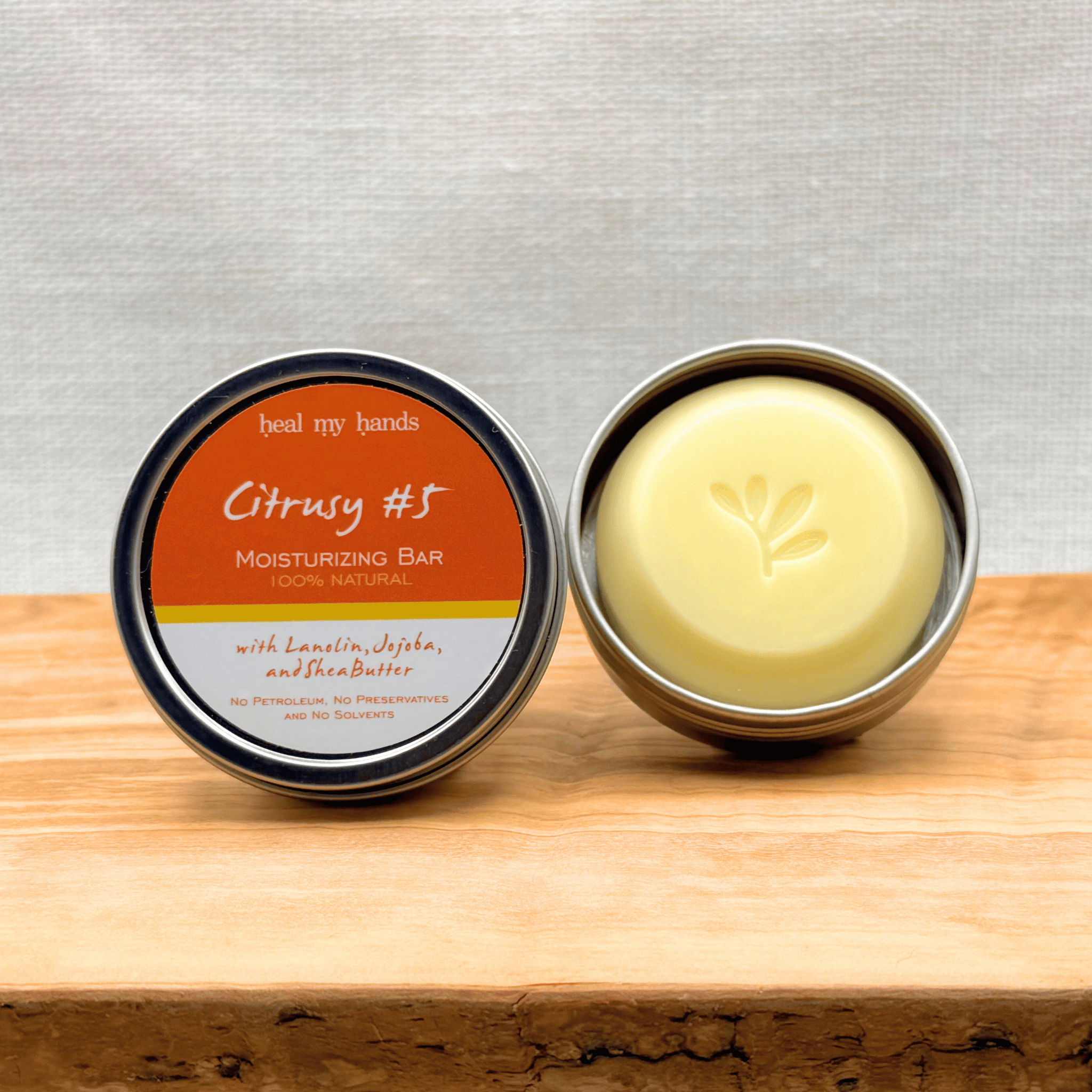 Heal My Hands Moisturizing bar in a tin with 'Citrusy #5' label on a wooden surface.