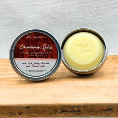 Cinnamon Spice moisturizing bar in a metal container on a wooden surface with a gray background