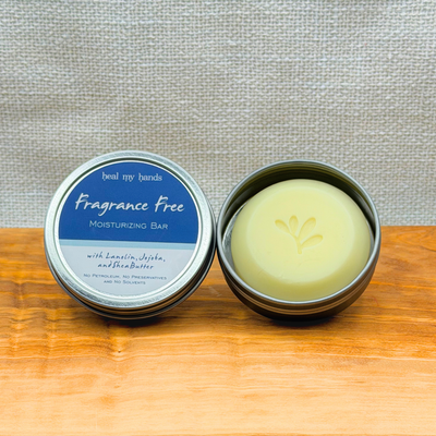 Heal My Hands Moisturizing bar in a tin with 'Fragrance Free' label on a wooden surface.