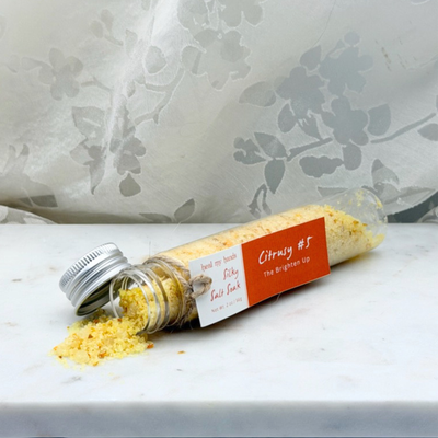 Citrusy #5 Silky Salt Soak 12 oz jar and 2 oz vial on marble surface.