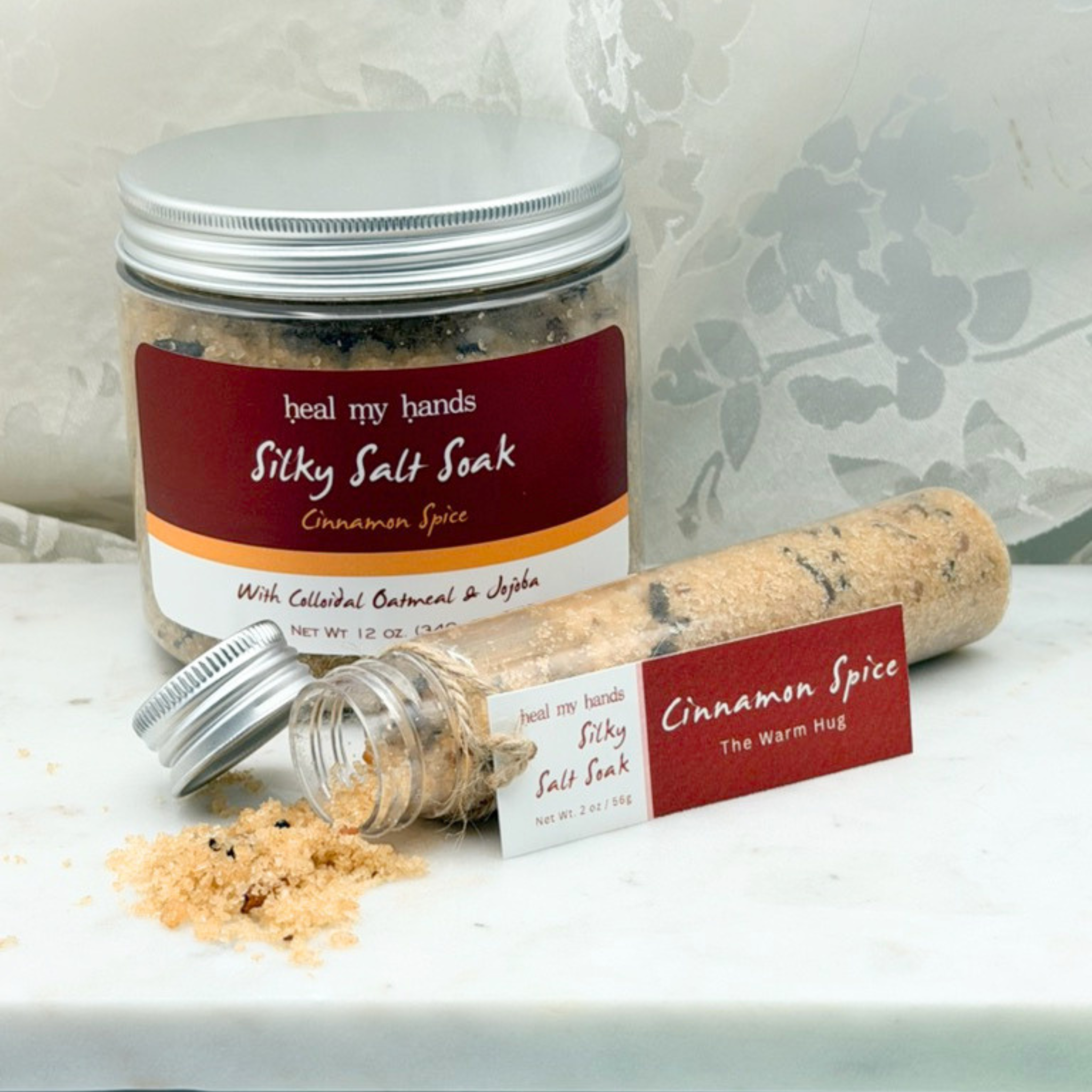 Cinnamon Spice Silky Salt Soak 12 oz jar and 2 oz vial on marble surface.