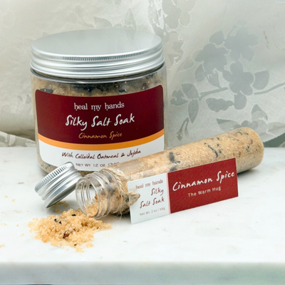 Cinnamon Spice Silky Salt Soak 12 oz jar and 2 oz vial on marble surface.