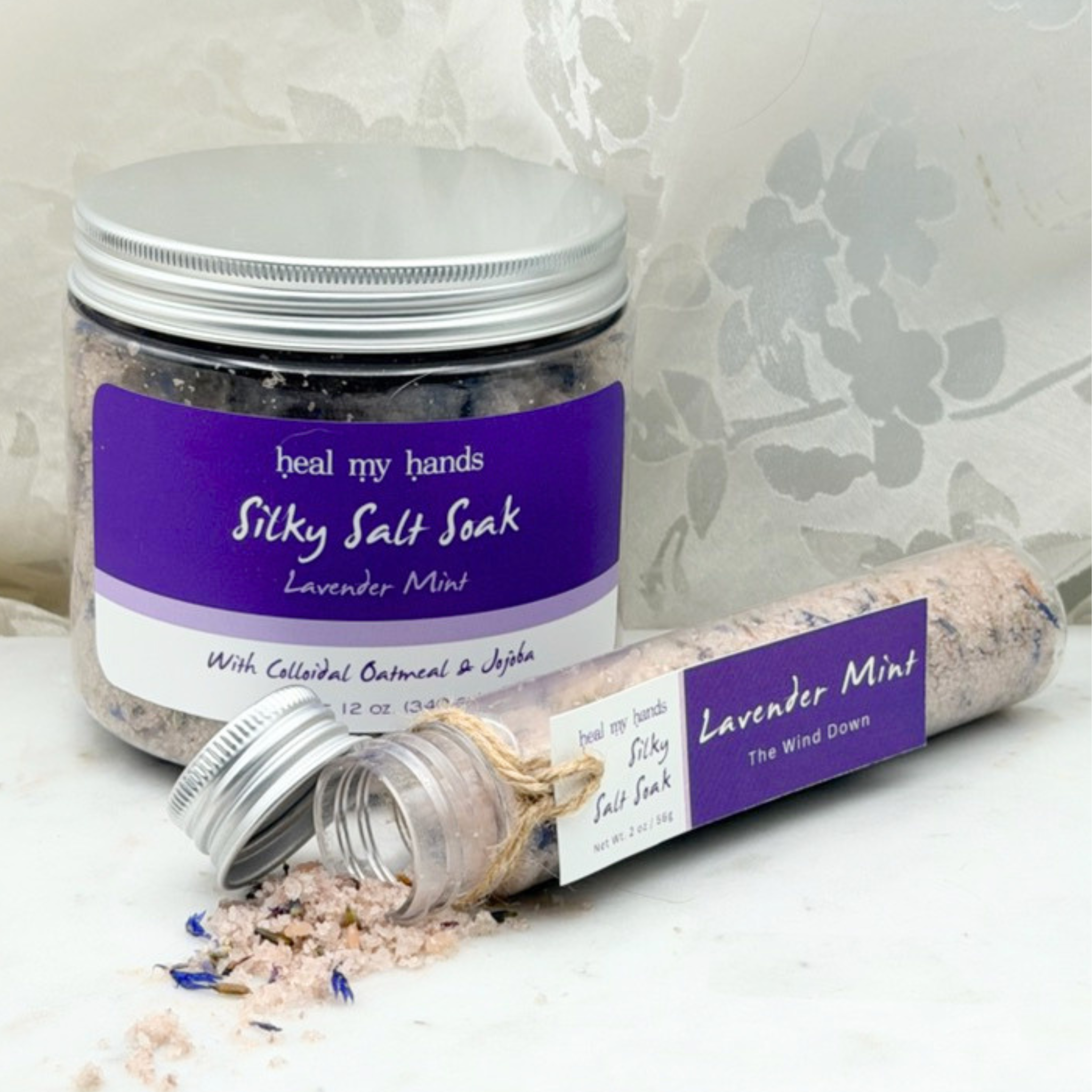 Lavender Mint Silky Salt Soak 12 oz jar and 2 oz vial on marble surface.