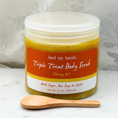 Citrusy #5  Triple Treat Body Scrub jar and small wooden spoon on marble surface.