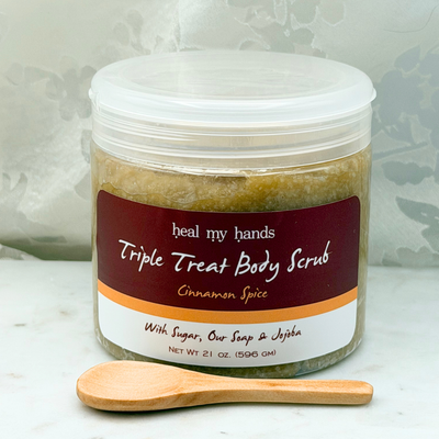 Cinnamon Spice Triple Treat Body Scrub jar and small wooden spoon on marble surface.